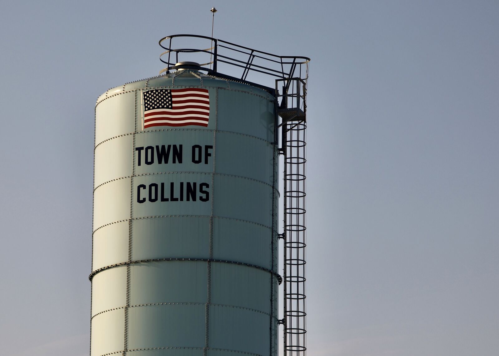 Town of Collins silo with American flag against a clear sky